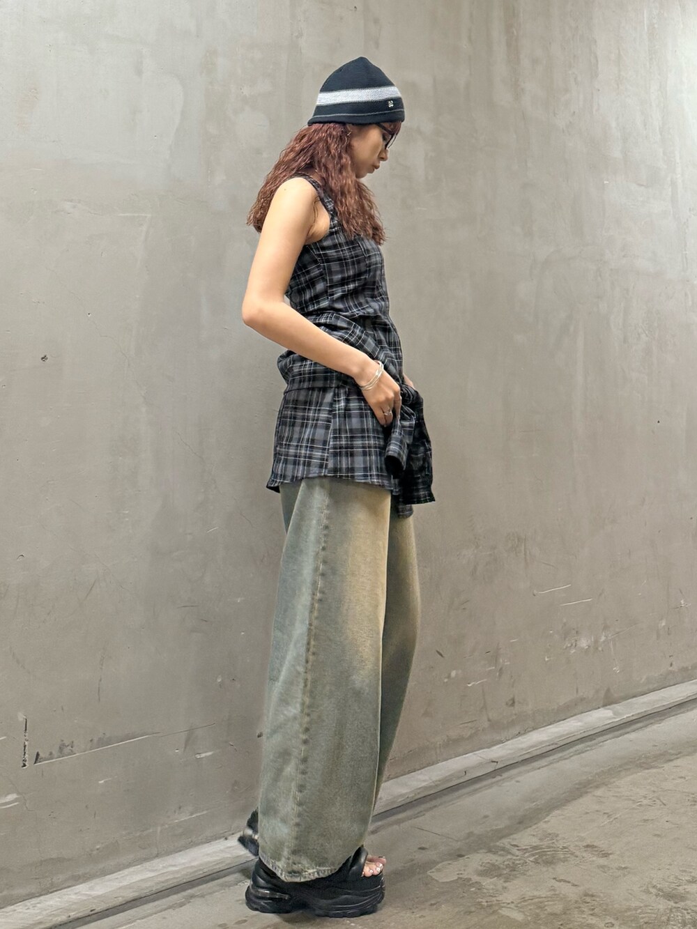 グレー系のワンピース、ブルー系のデニムパンツ、ブラック系のサンダルを着用したレディースの夏コーディネートの2枚目の写真