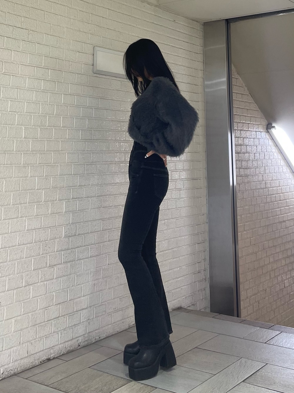 グレー系のニット/セーター、ブラック系のデニムパンツ、ブラック系のブーツを着用したレディースの冬コーディネートの2枚目の写真