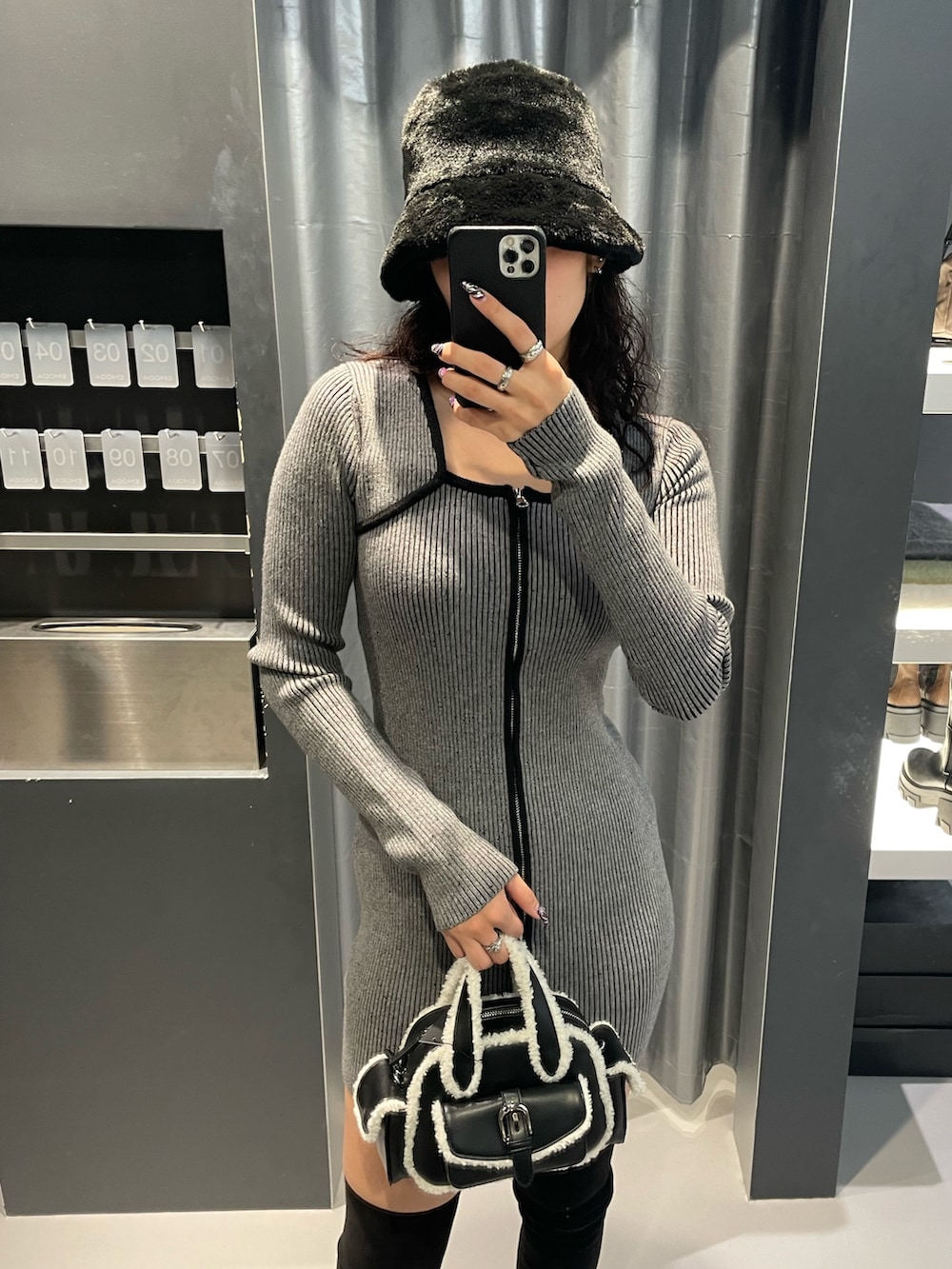 グレー系のワンピース、ブラック系のハンドバッグ、ブラック系のブーツを着用したレディースの冬コーディネートの4枚目の写真