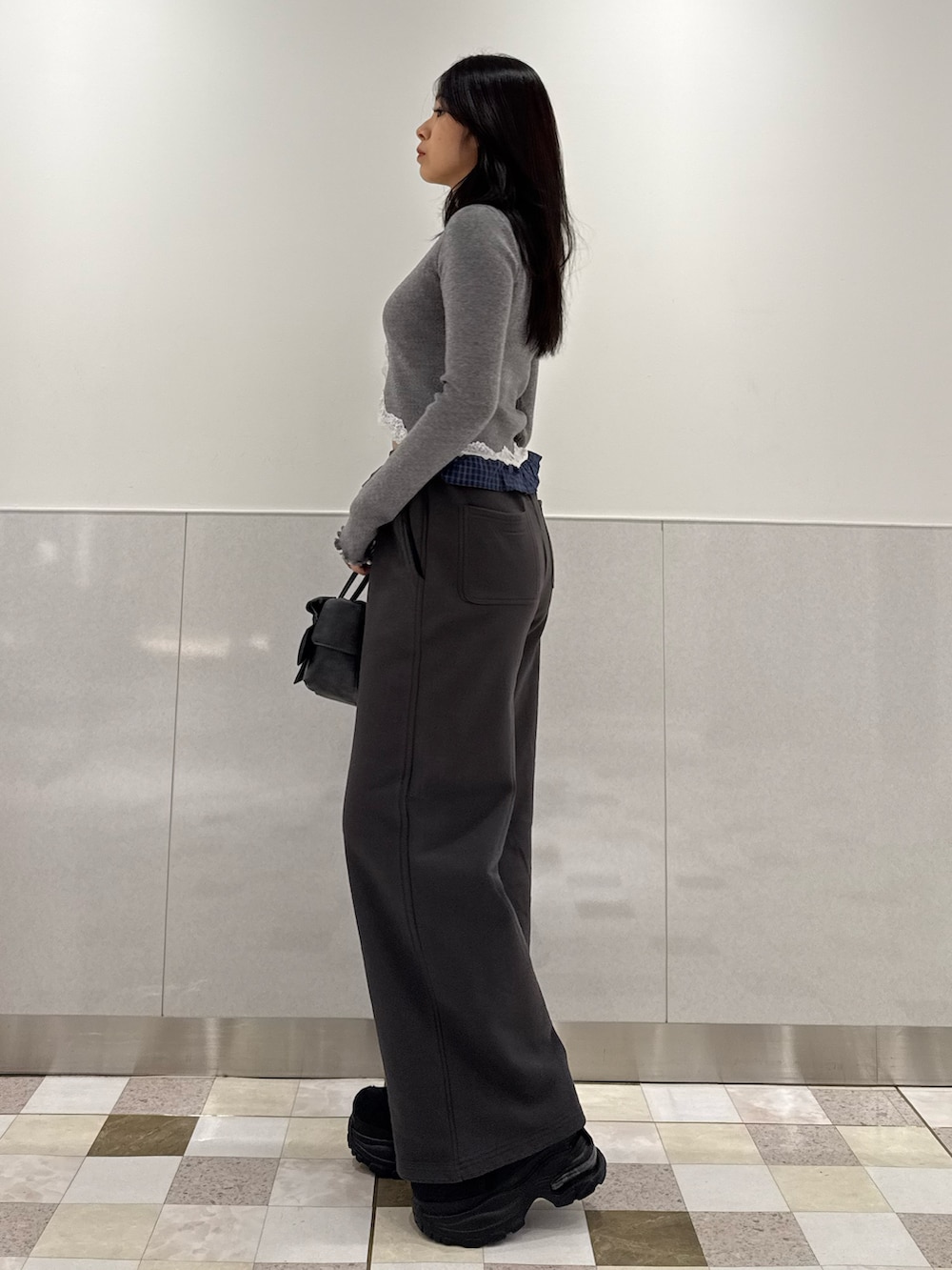 グレー系のニット/セーター、グレー系のスウェットパンツ、ブラック系のハンドバッグを着用したレディースの春コーディネートの2枚目の写真