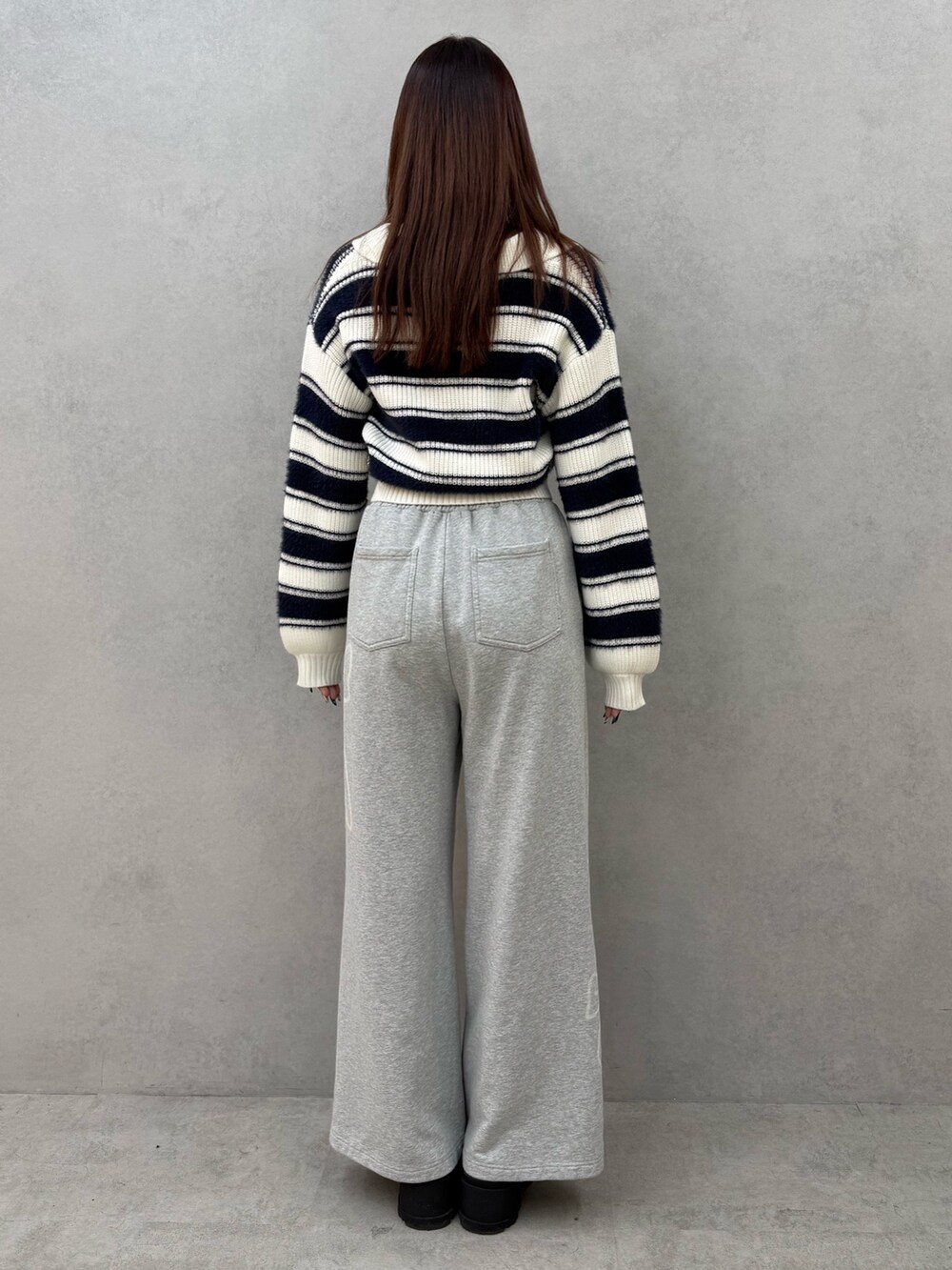 ブルー系のニット/セーター、グレー系のスウェットパンツ、ブラック系のブーツを着用したレディースの冬コーディネートの3枚目の写真