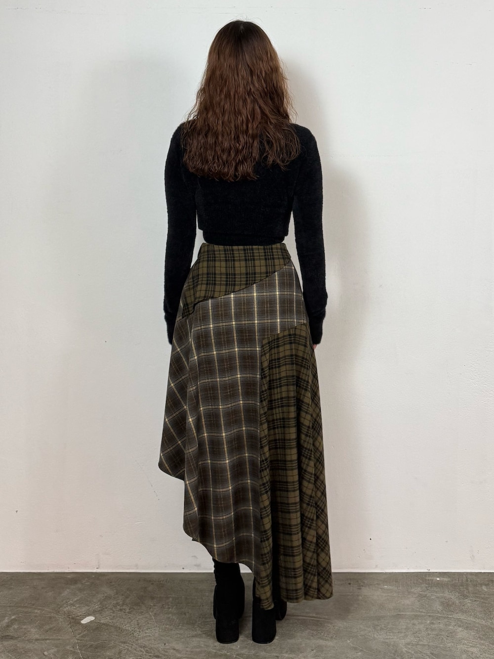 ブラック系のニット/セーター、グリーン系のスカート、ブラック系のブーツを着用したレディースの秋コーディネートの3枚目の写真