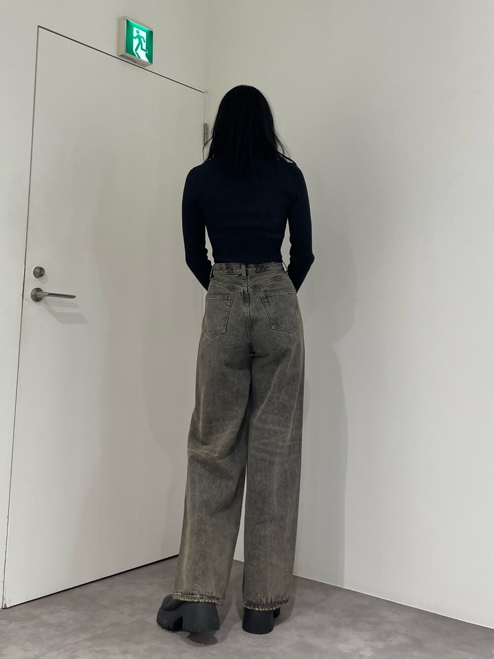 ブラック系のニット/セーター、グレー系のデニムパンツ、ブラック系のブーツを着用したレディースの春コーディネートの3枚目の写真