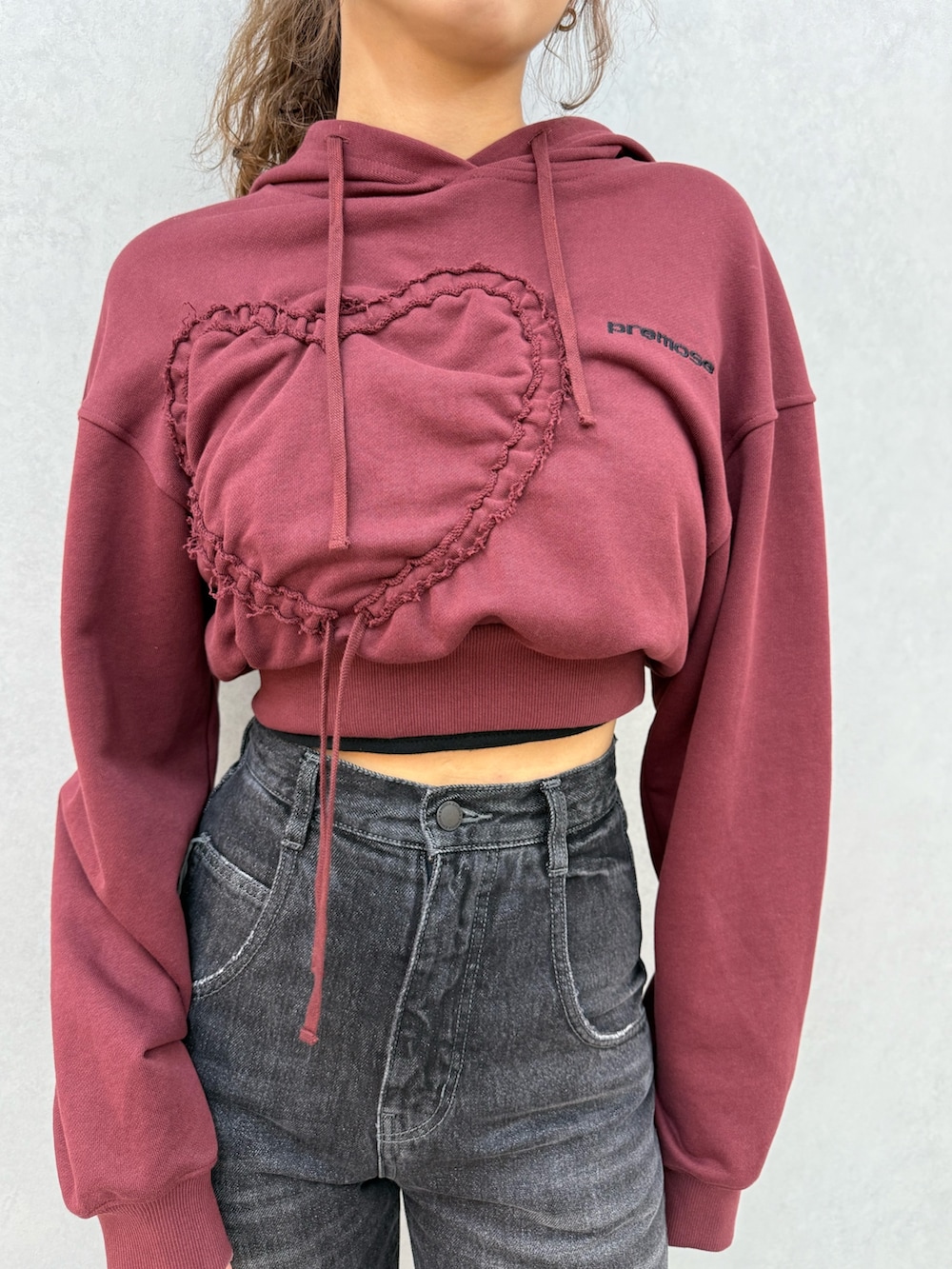 レッド系のパーカー、ブラック系のデニムパンツ、ブラック系のブーツを着用したレディースの秋コーディネートの4枚目の写真