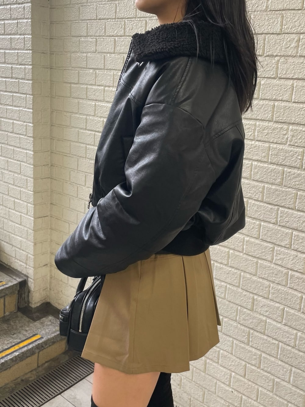 ブラック系のニット/セーター、ブラック系のブルゾン、ベージュ系のスカートを着用したレディースの秋コーディネートの5枚目の写真