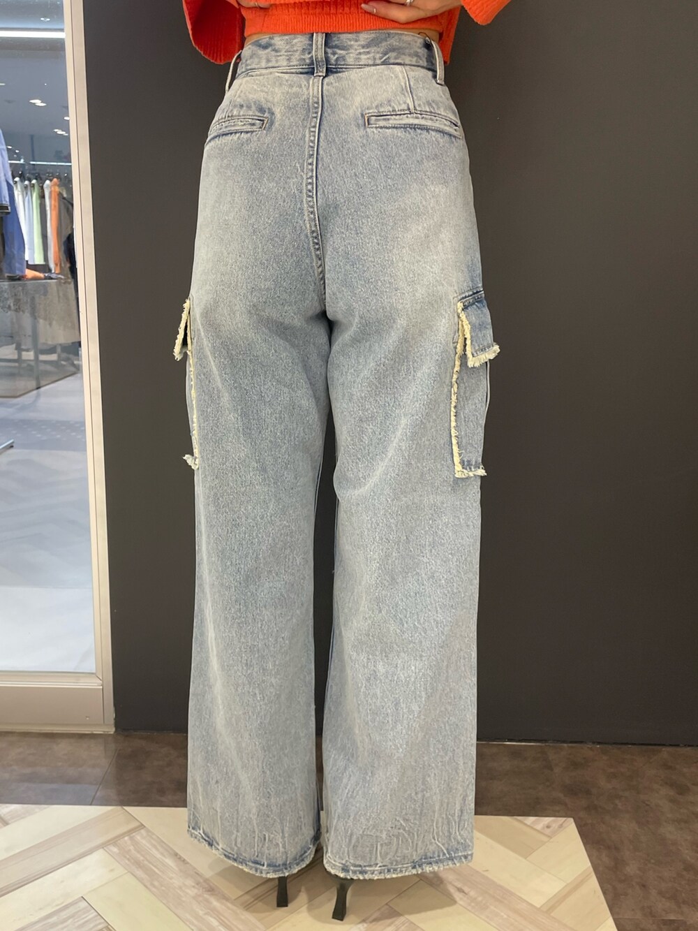 オレンジ系のニット/セーター、ブルー系のデニムパンツ、ブラック系のパンプスを着用したレディースの春コーディネートの9枚目の写真