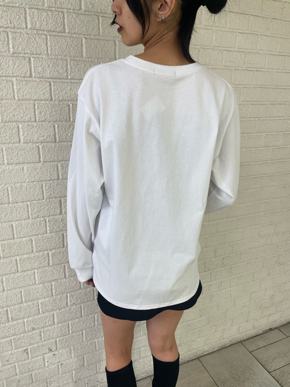 ホワイト系のTシャツ/カットソー、ホワイト系のダウンベスト、ブラック系のスカートを着用したレディースの秋コーディネートの8枚目の写真