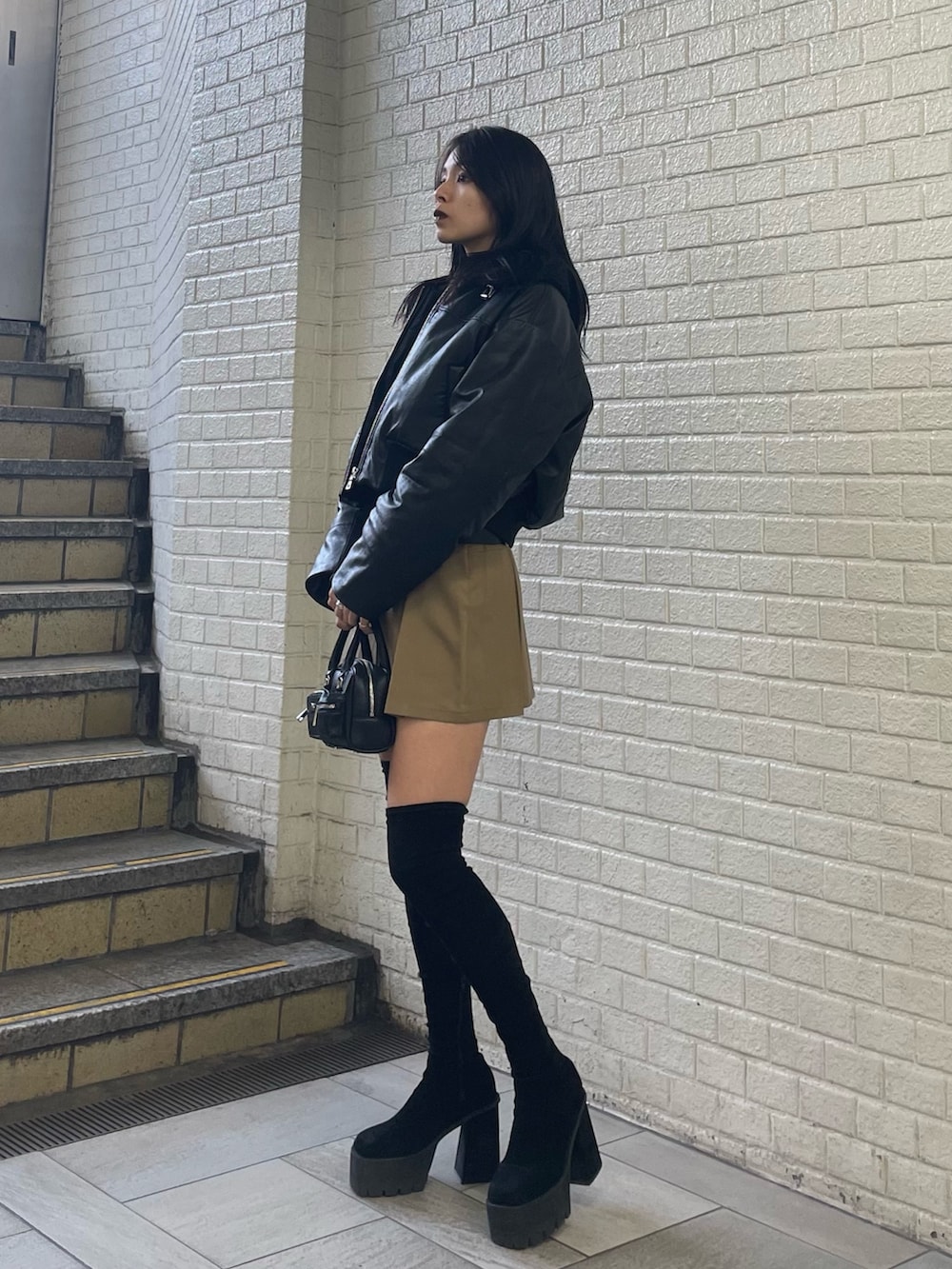 ブラック系のニット/セーター、ブラック系のブルゾン、ベージュ系のスカートを着用したレディースの秋コーディネートの2枚目の写真