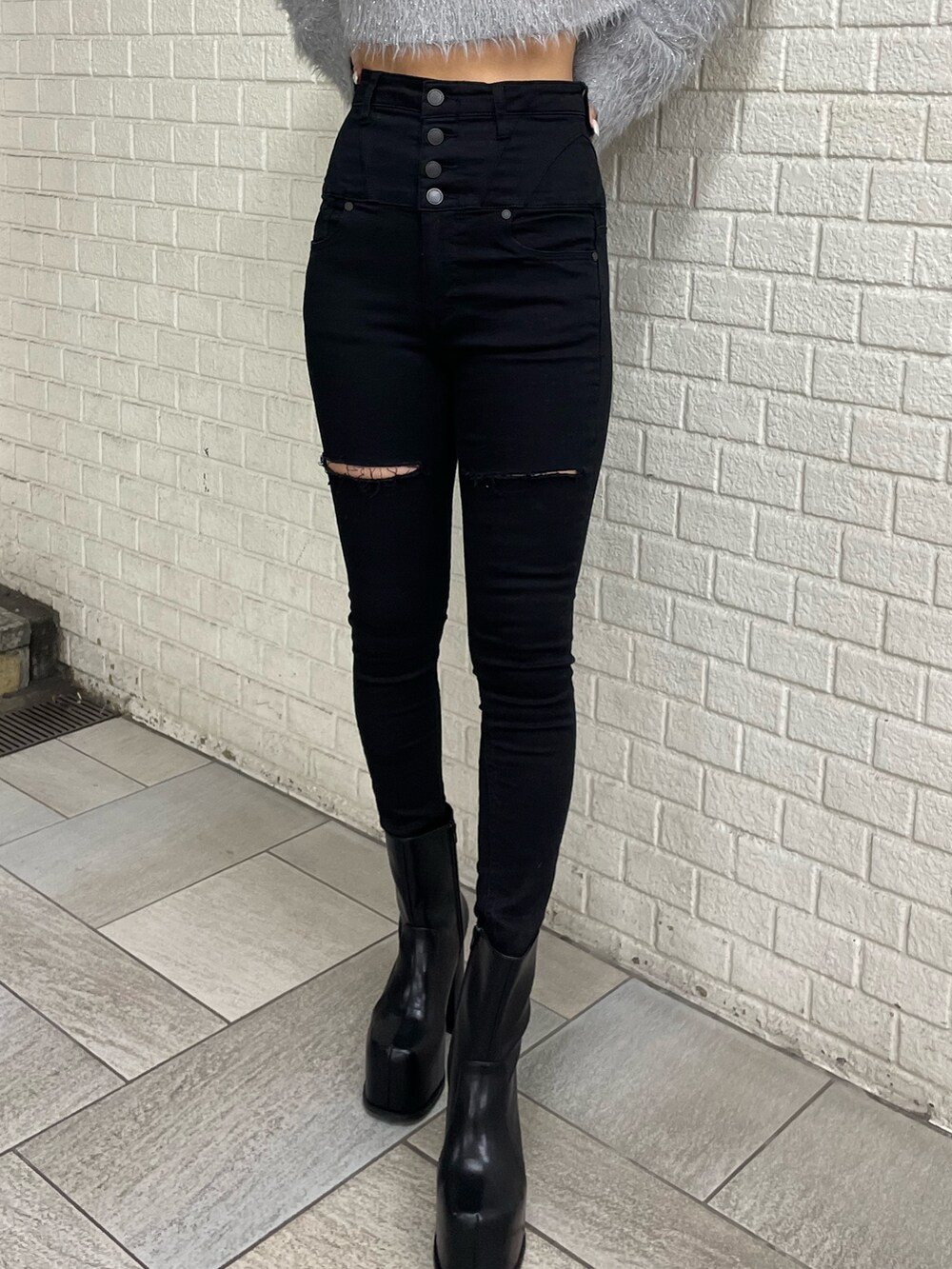 グレー系のニット/セーター、ブラック系のデニムパンツ、ブラック系のブーツを着用したレディースの冬コーディネートの7枚目の写真