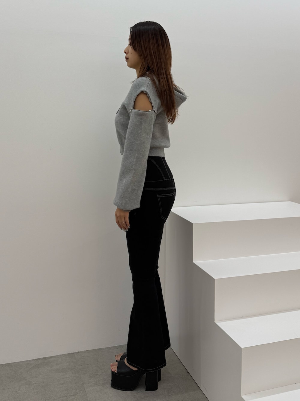 グレー系のパーカー、ブラック系のデニムパンツ、ブラック系のサンダルを着用したレディースの冬コーディネートの2枚目の写真