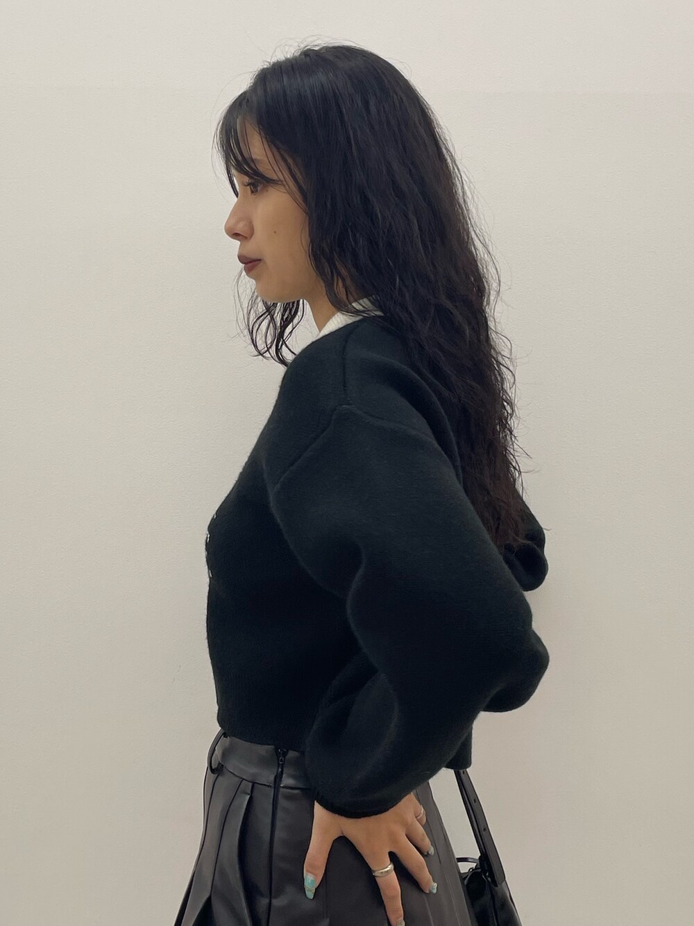 ブラック系のニット/セーター、ブルー系のデニムパンツ、ブラック系のショルダーバッグを着用したレディースの夏コーディネートの5枚目の写真