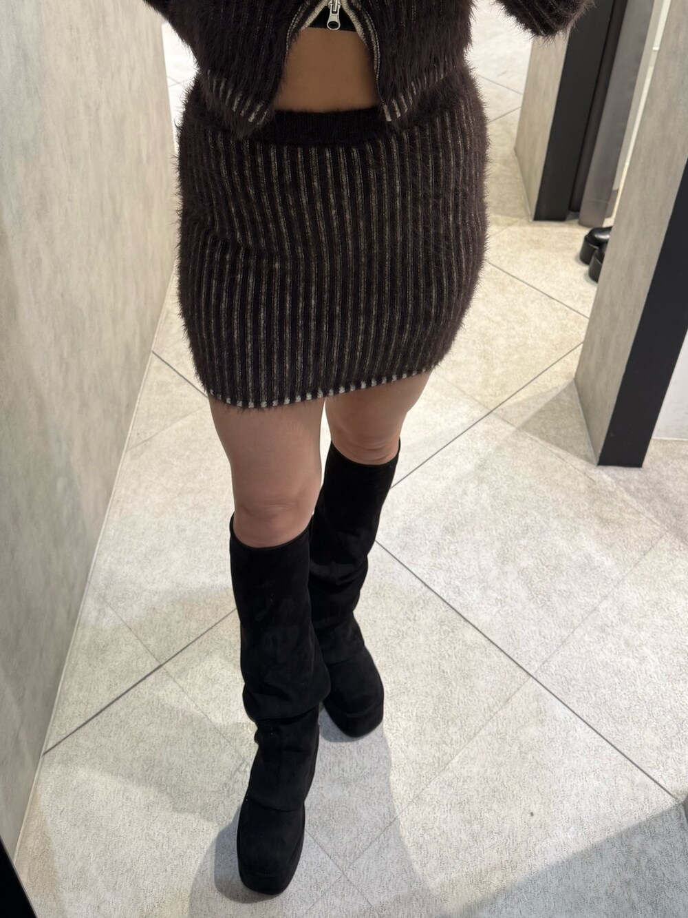 ブラウン系のニット/セーター、ブラウン系のスカート、ブラック系のブーツを着用したレディースの秋コーディネートの6枚目の写真