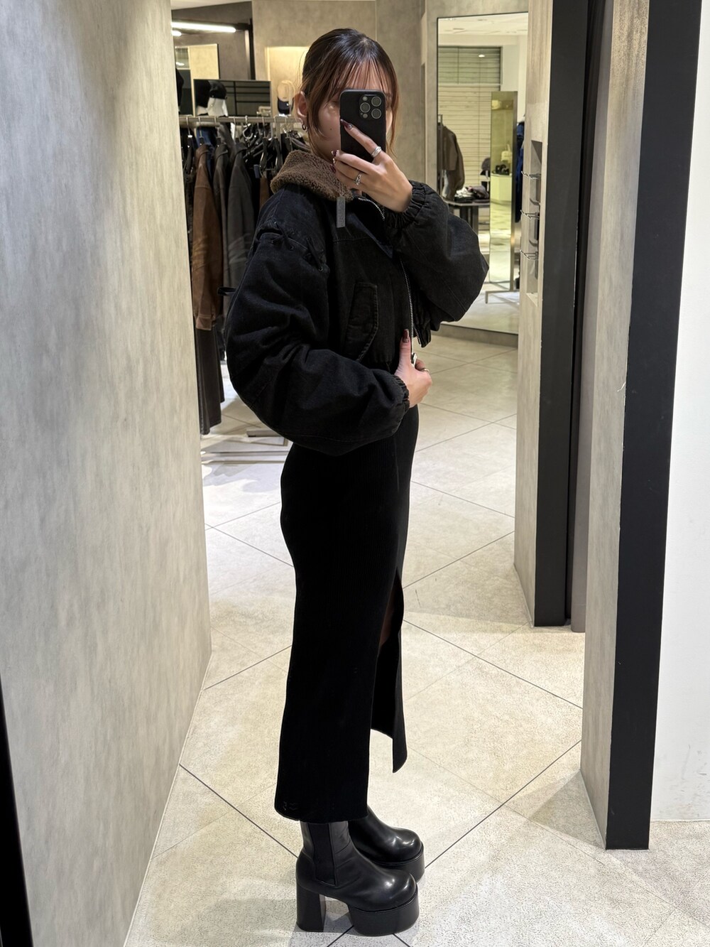 ブラック系のブルゾン、ブラック系のワンピース、ブラック系のブーツを着用したレディースの秋コーディネートの2枚目の写真