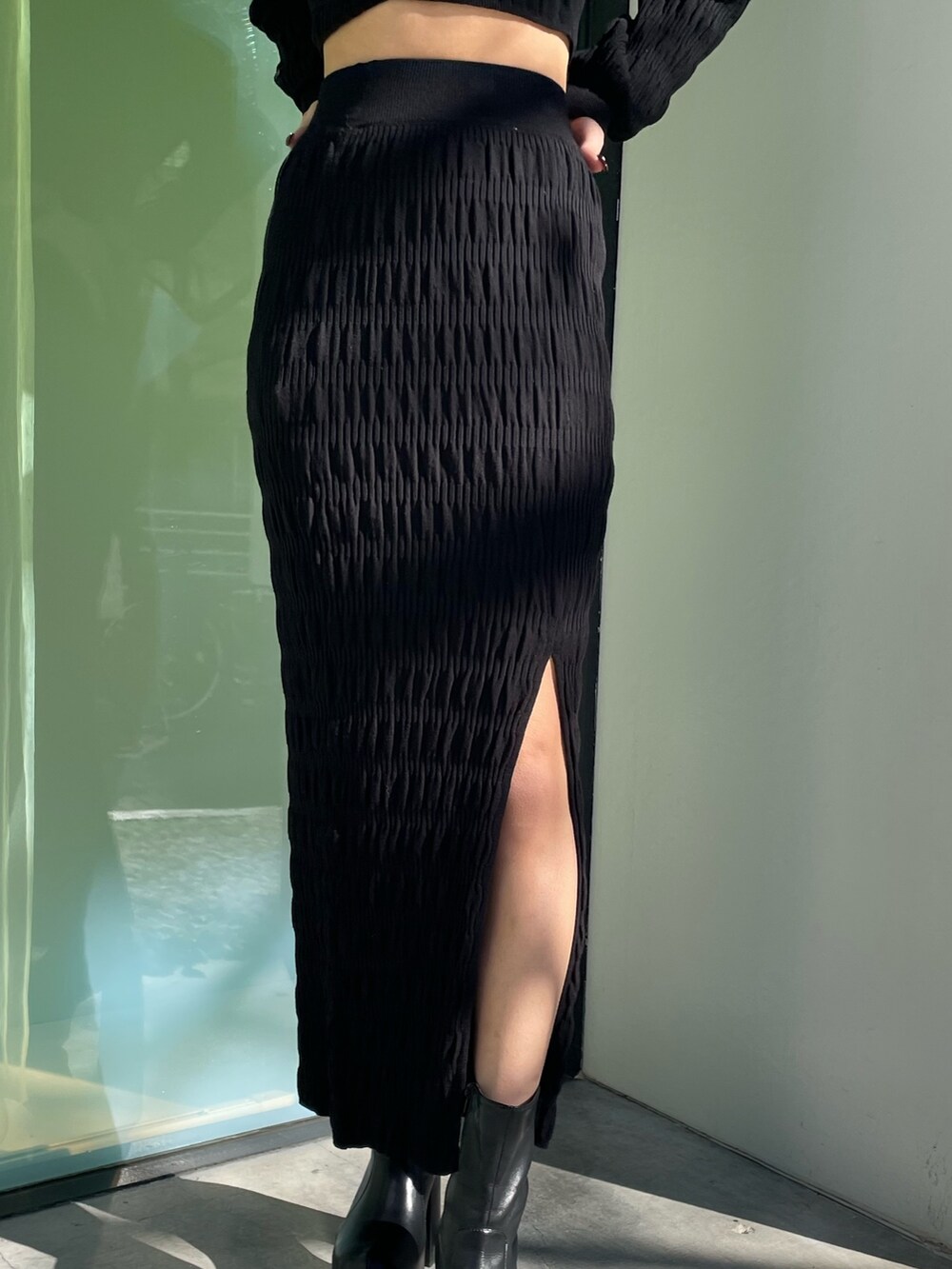 ブラック系のニット/セーター、ブラック系のスカート、ブラック系のブーツを着用したレディースの春コーディネートの7枚目の写真