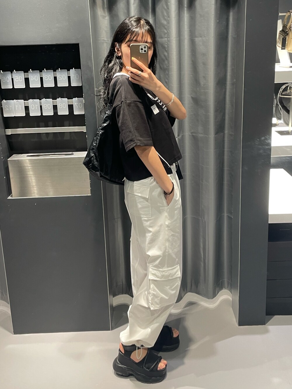ブラック系のTシャツ/カットソー、ブラック系のハンドバッグ、ホワイト系のカーゴパンツを着用したレディースの春コーディネートの2枚目の写真