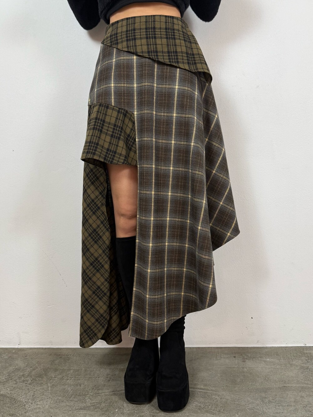 ブラック系のニット/セーター、グリーン系のスカート、ブラック系のブーツを着用したレディースの秋コーディネートの5枚目の写真