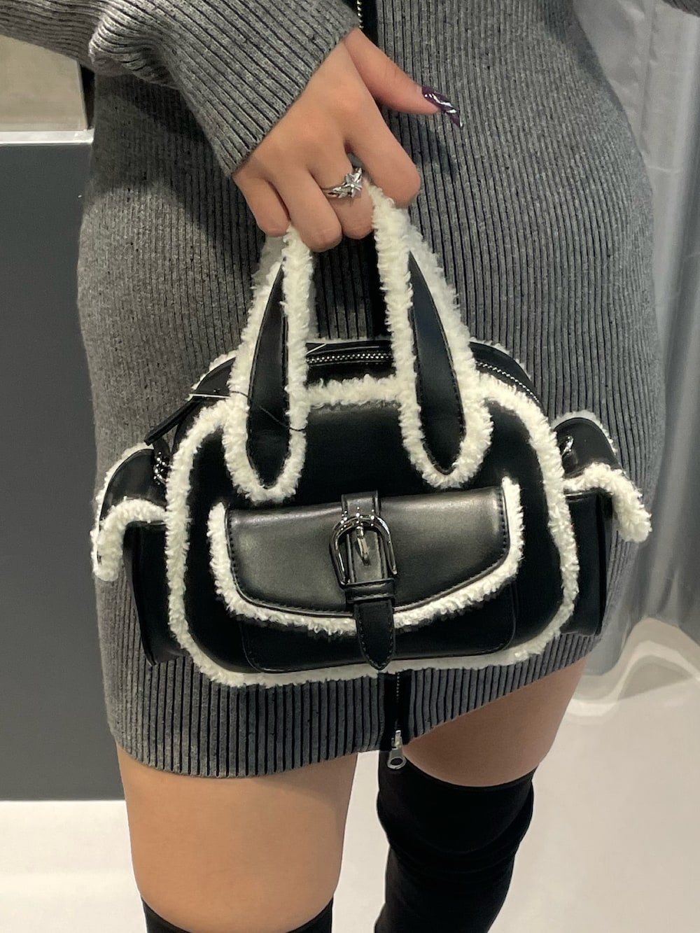 グレー系のワンピース、ブラック系のハンドバッグ、ブラック系のブーツを着用したレディースの冬コーディネートの6枚目の写真