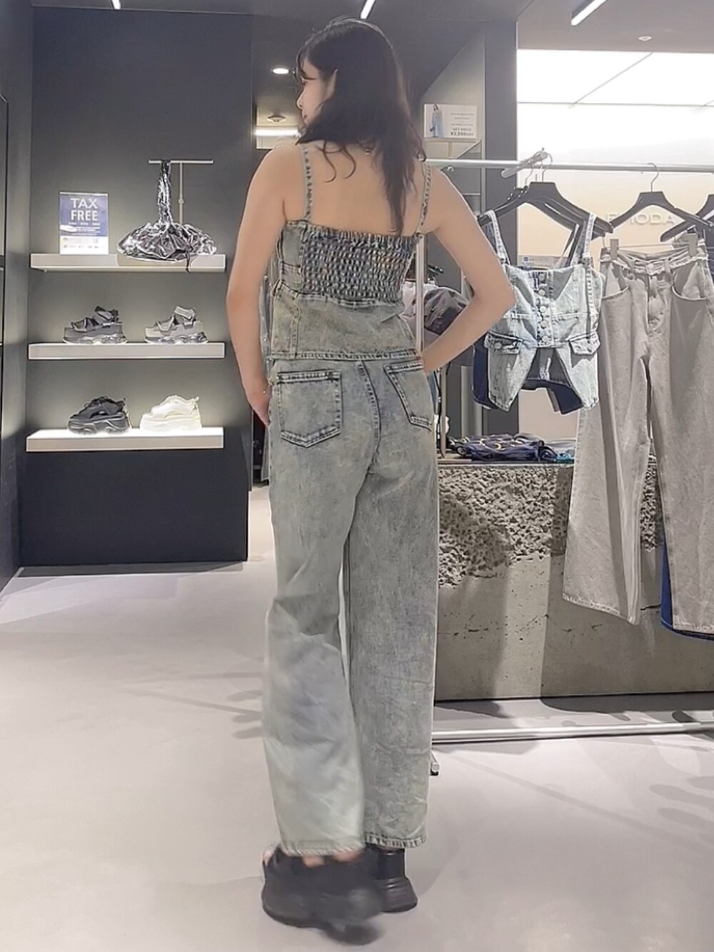 ブルー系のキャミソール、ブルー系のデニムパンツ、ブラック系のサンダルを着用したレディースの夏コーディネートの3枚目の写真
