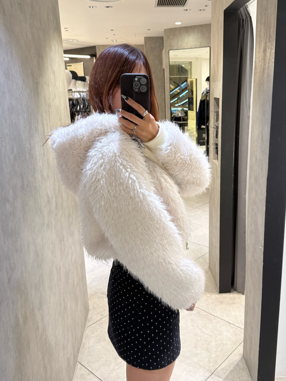 ホワイト系のブルゾン、ブラック系のニット/セーター、ブルー系のスカートを着用したレディースの秋コーディネートの5枚目の写真