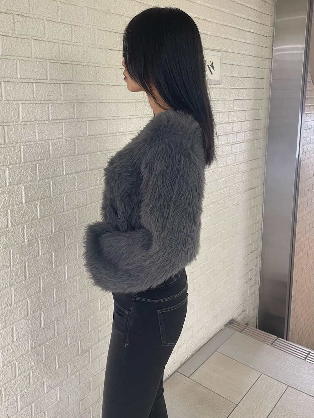 グレー系のニット/セーター、ブラック系のデニムパンツ、ブラック系のブーツを着用したレディースの冬コーディネートの5枚目の写真