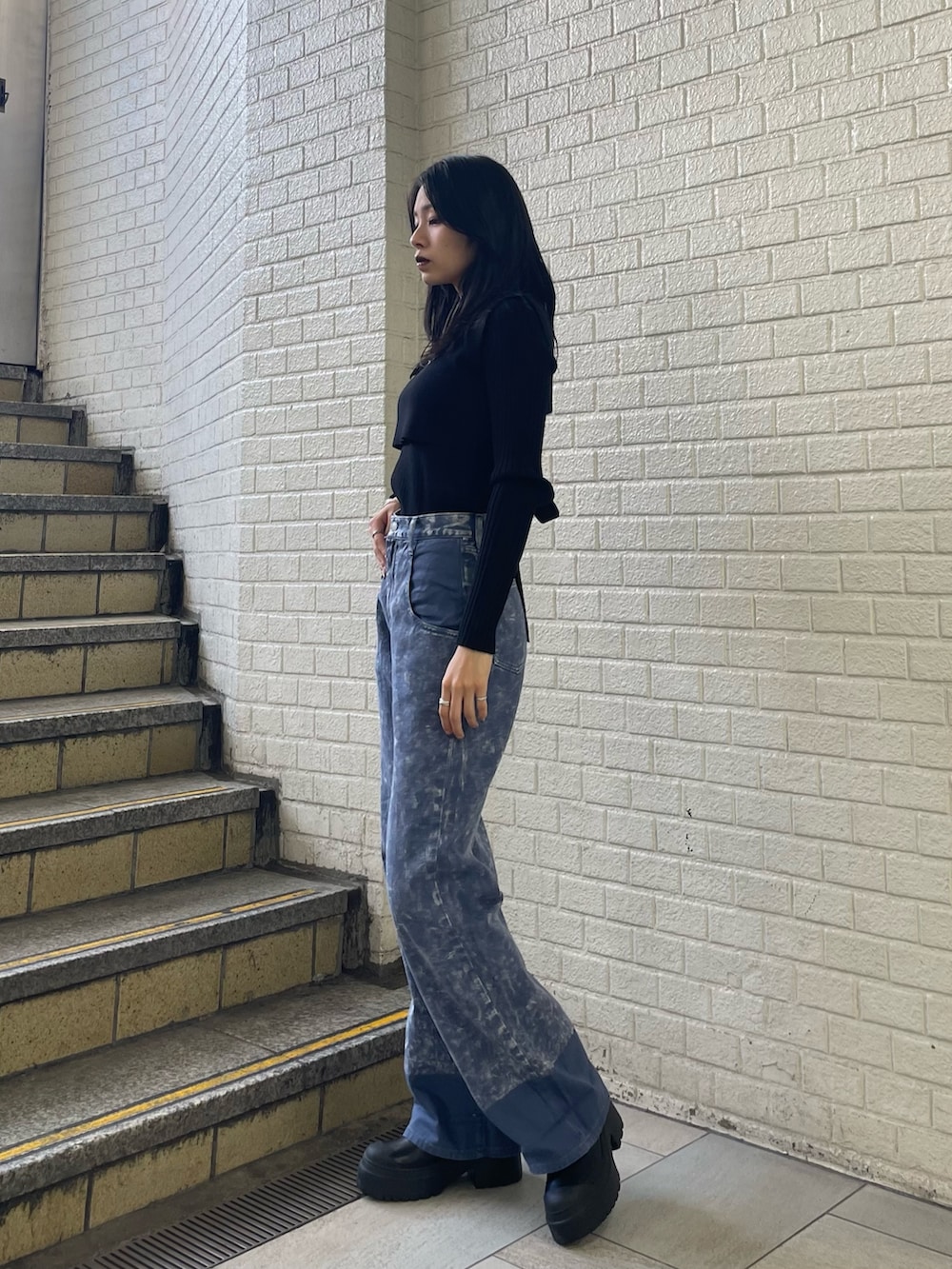 ブラック系のニット/セーター、パープル系のデニムパンツ、ブラック系のブーツを着用したレディースの秋コーディネートの2枚目の写真