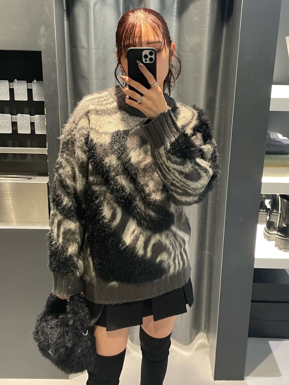 グレー系のニット/セーター、ブラック系のスカート、ブラック系のハンドバッグを着用したレディースの冬コーディネートの4枚目の写真