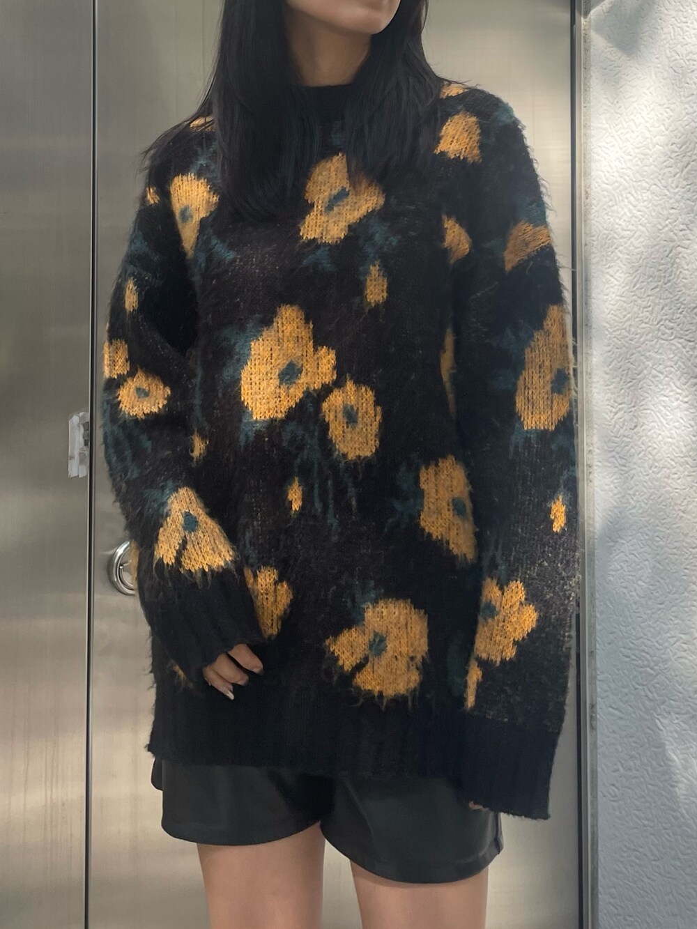 オレンジ系のニット/セーター、ブラック系のムートンコート、ブラック系のその他パンツを着用したレディースの秋コーディネートの6枚目の写真