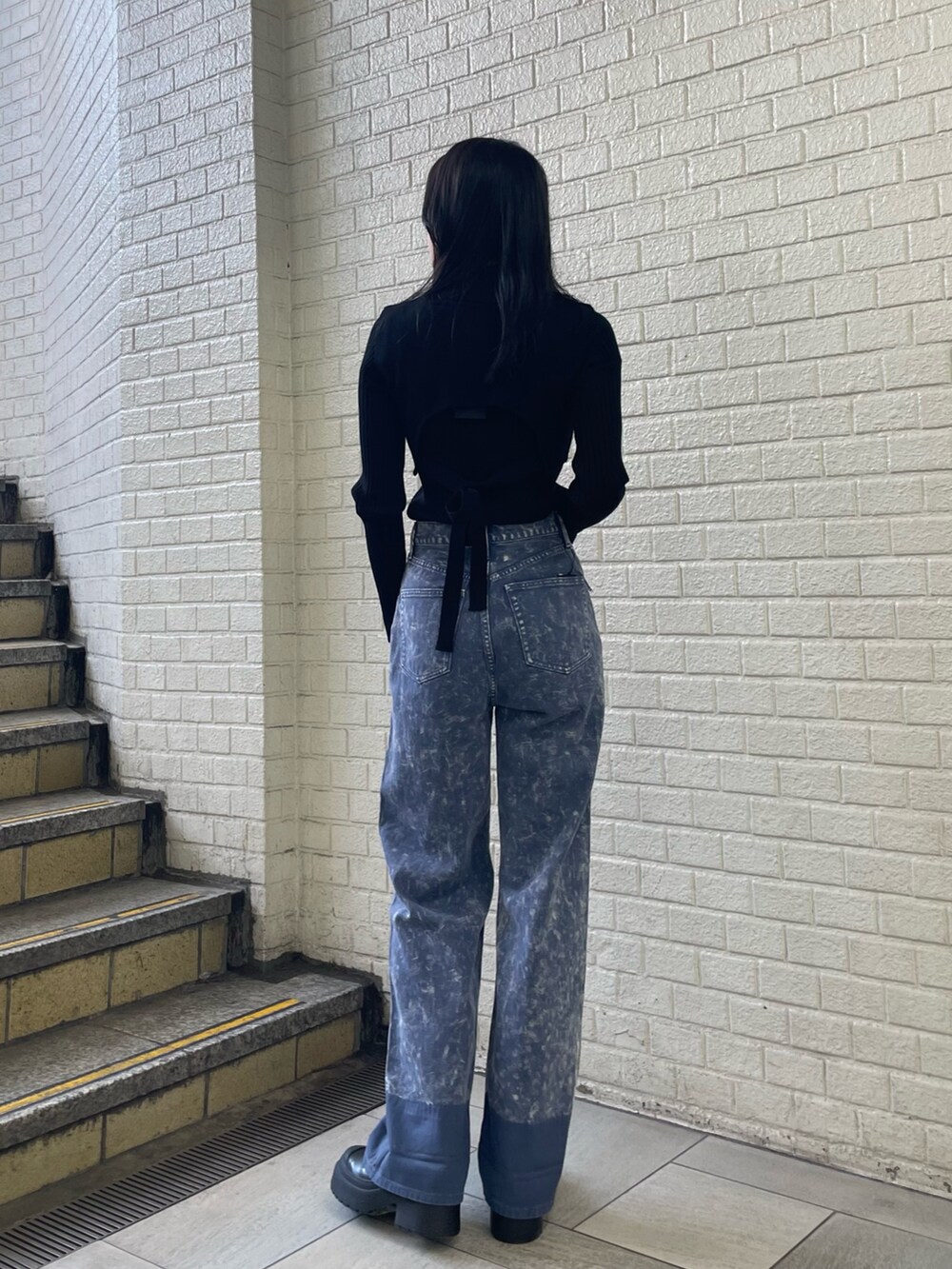 ブラック系のニット/セーター、パープル系のデニムパンツ、ブラック系のブーツを着用したレディースの秋コーディネートの3枚目の写真