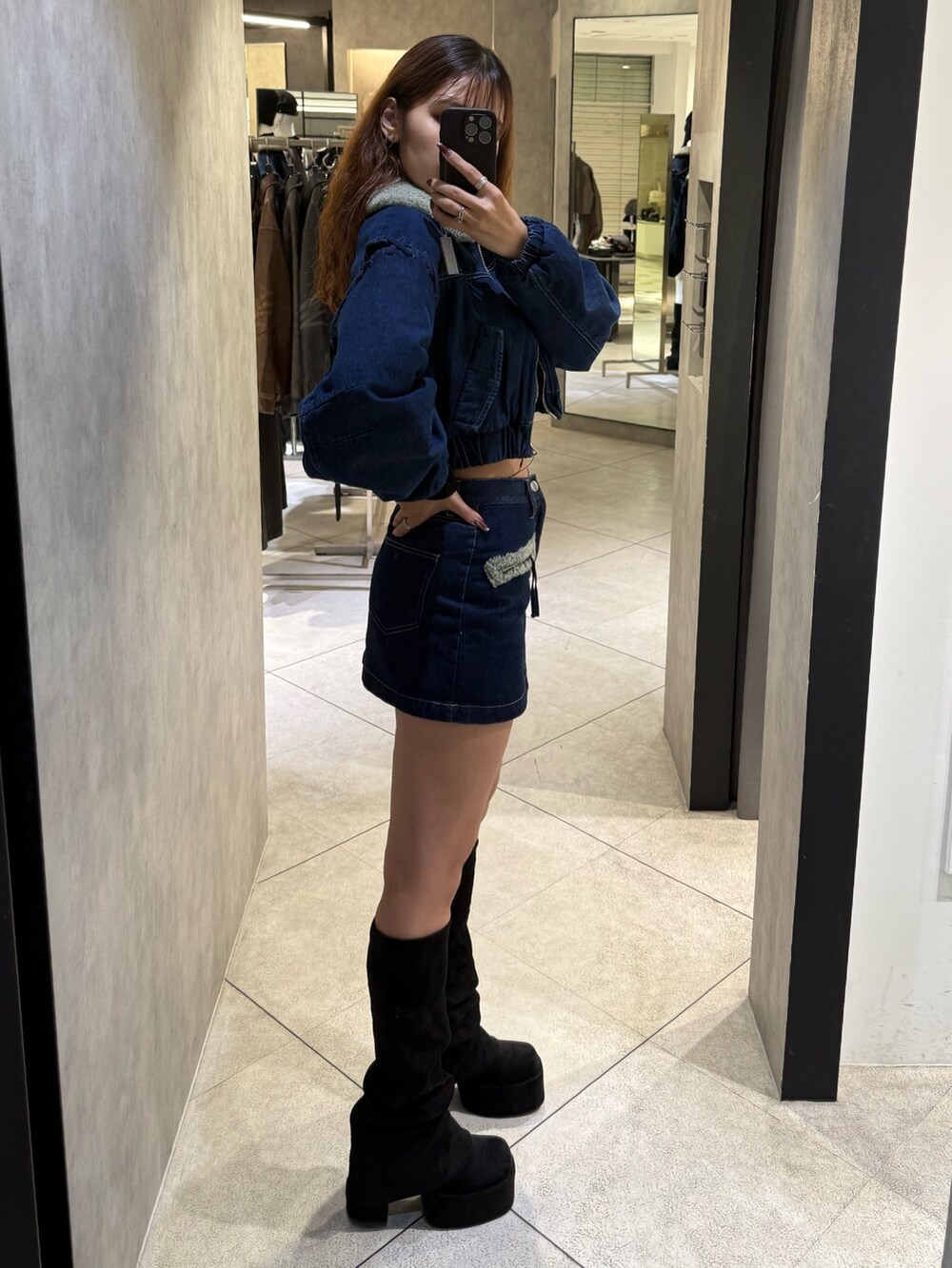 ブルー系のブルゾン、ブラック系のニット/セーター、ブルー系のスカートを着用したレディースの秋コーディネートの2枚目の写真