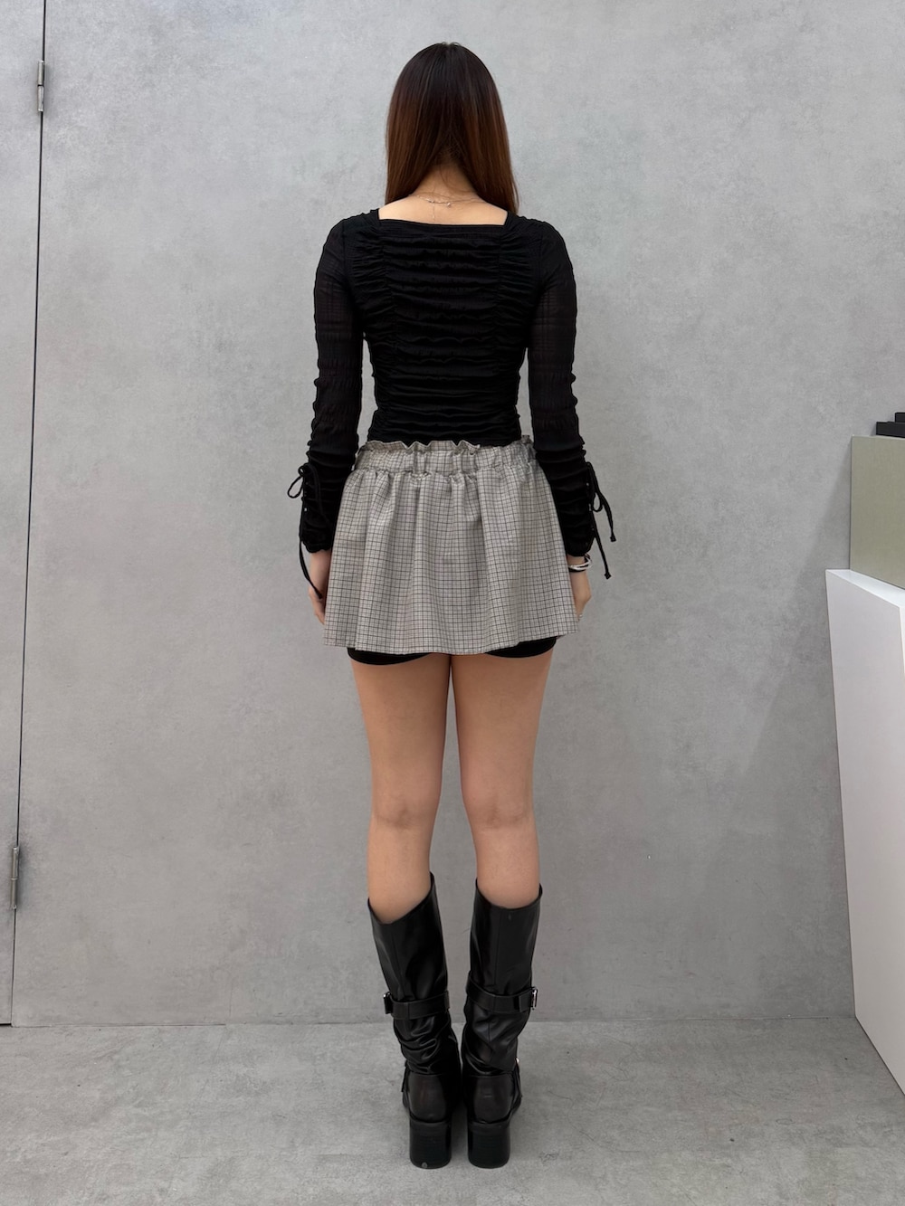 ブラック系のTシャツ/カットソー、ブラック系のスカート、ブラック系のブーツを着用したレディースの冬コーディネートの3枚目の写真