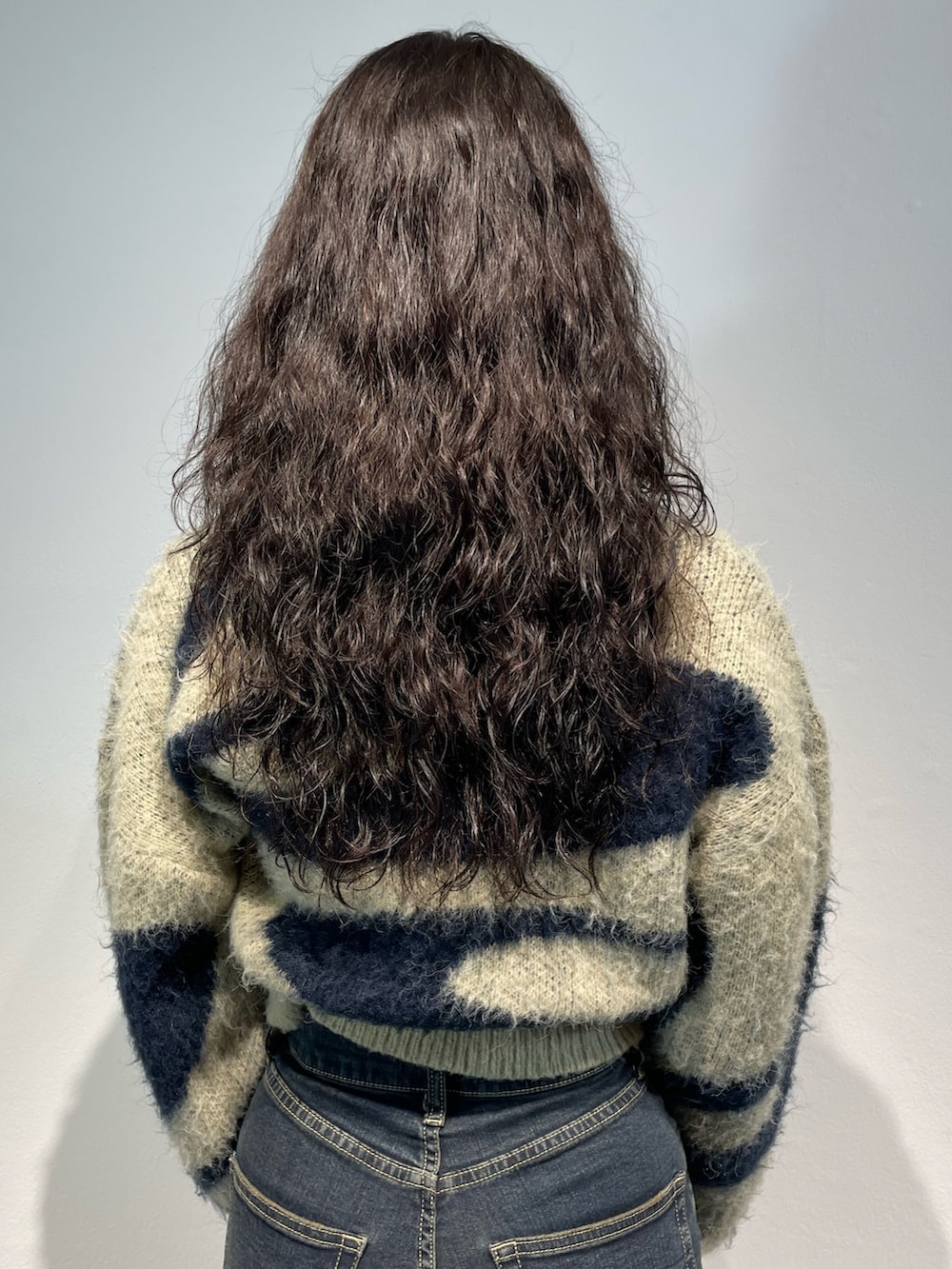 ブルー系のニット/セーター、ブラック系のスカート、ブラック系のハンドバッグを着用したレディースの秋コーディネートの6枚目の写真