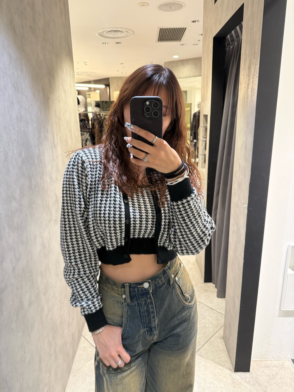 ブラック系のニット/セーター、ブルー系のデニムパンツ、ブラック系のブーツを着用したレディースの秋コーディネートの4枚目の写真