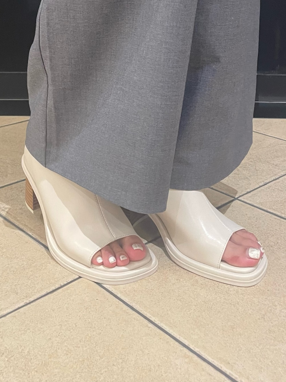 ホワイト系のニット/セーター、ホワイト系のハンドバッグ、グレー系のベストを着用したレディースの夏コーディネートの8枚目の写真