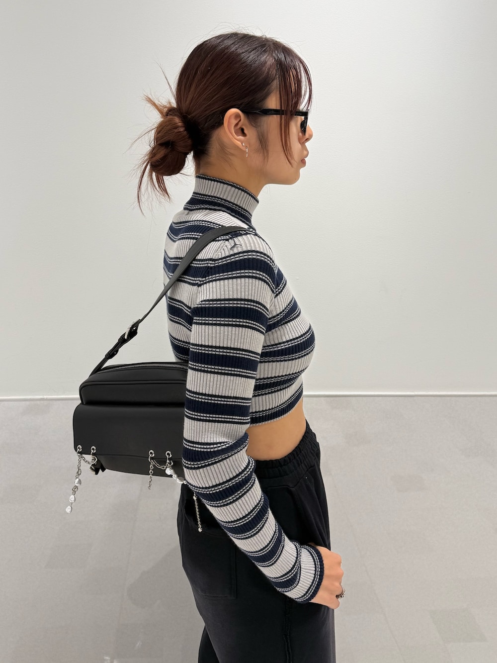 グレー系のニット/セーター、ブラック系のスウェットパンツ、ブラック系のブーツを着用したレディースの秋コーディネートの5枚目の写真