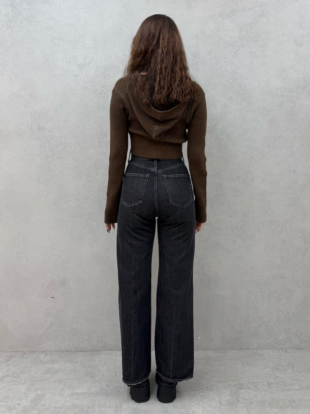 グリーン系のニット/セーター、ブラック系のデニムパンツ、ブラック系のブーツを着用したレディースの秋コーディネートの3枚目の写真