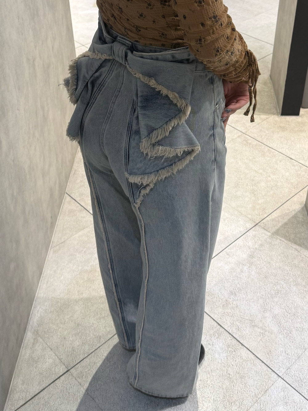 ベージュ系のTシャツ/カットソー、ブルー系のデニムパンツ、ブラック系のスニーカーを着用したレディースの春コーディネートの5枚目の写真