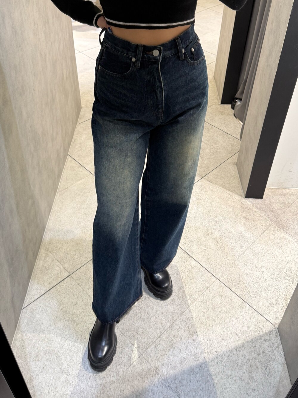 ブラック系のブーツ、ブラック系のニット/セーター、ブルー系のデニムパンツを着用したレディースの秋コーディネートの6枚目の写真