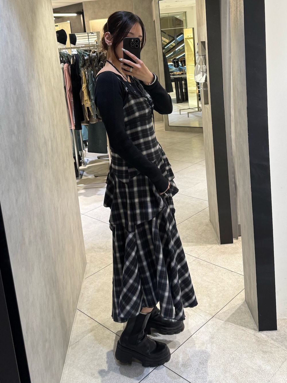 ブラック系のニット/セーター、ブラック系のワンピース、ブラック系のブーツを着用したレディースの春コーディネートの2枚目の写真