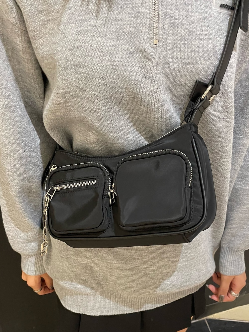 グレー系のワンピース、ブラック系のハンドバッグ、ブラック系のスカートを着用したレディースの秋コーディネートの7枚目の写真