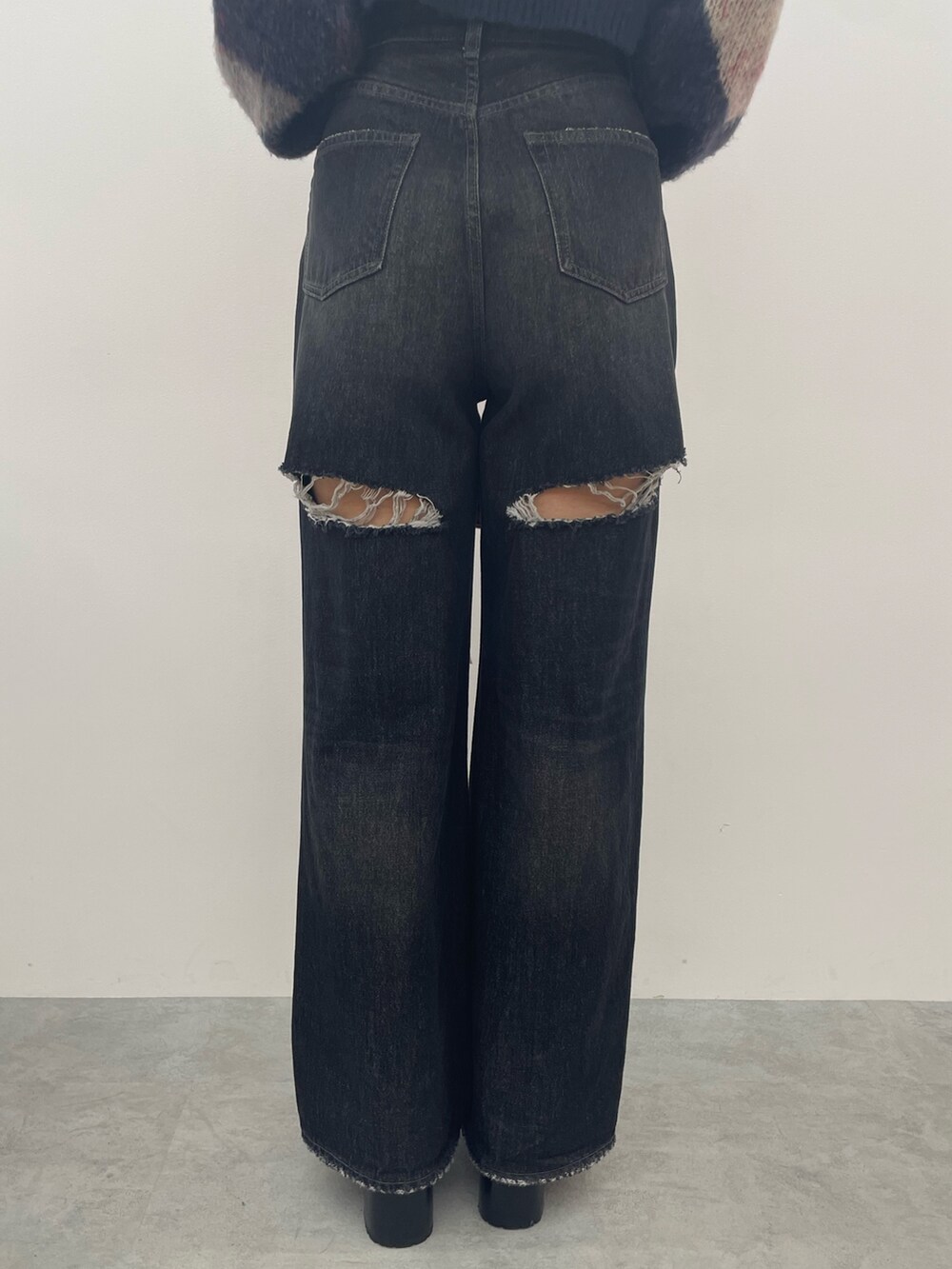 ブラック系のワンピース、ブラック系のデニムパンツ、ブラック系のブーツを着用したレディースの秋コーディネートの8枚目の写真