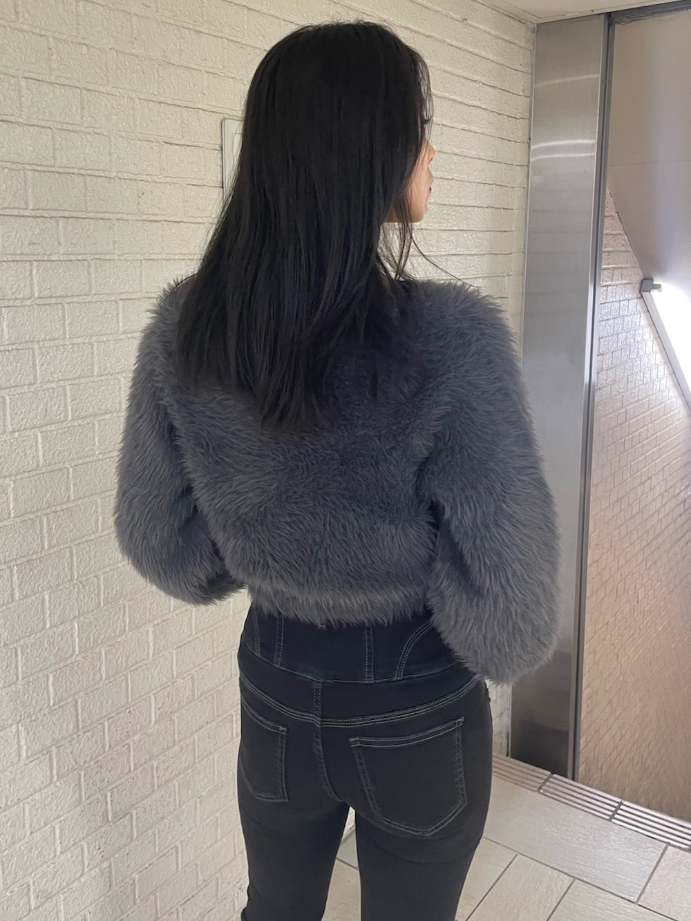 グレー系のニット/セーター、ブラック系のデニムパンツ、ブラック系のブーツを着用したレディースの冬コーディネートの6枚目の写真