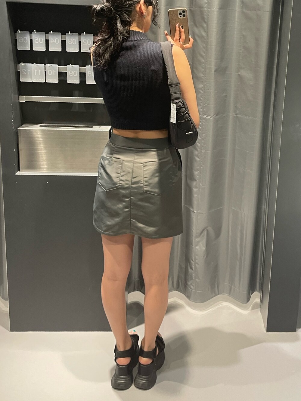 ブラック系のニット/セーター、グレー系のスカート、ブラック系のショルダーバッグを着用したレディースの夏コーディネートの3枚目の写真