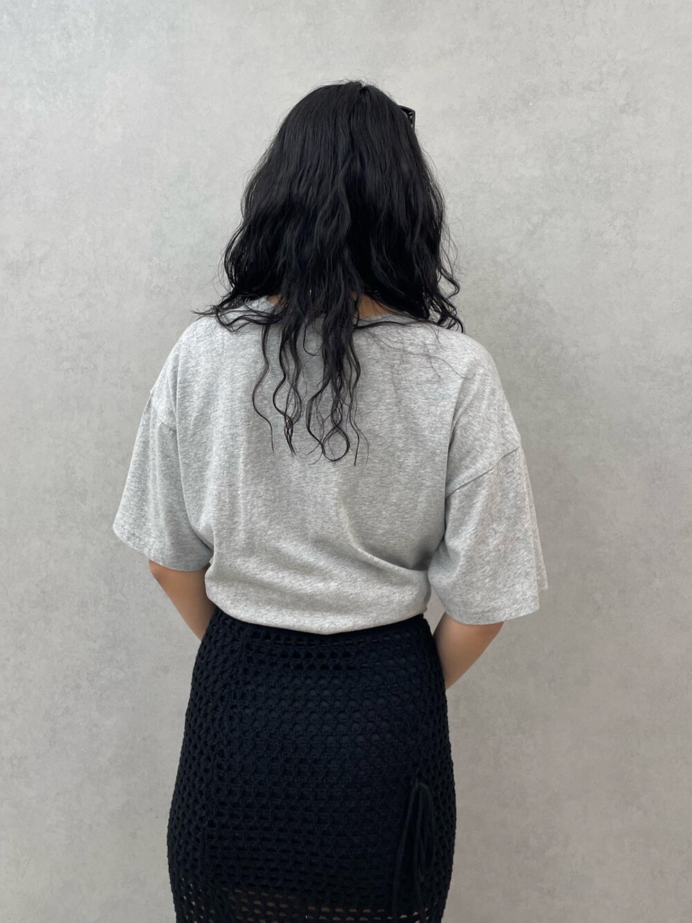 グレー系のTシャツ/カットソー、ブラック系のスカート、ブラック系のサンダルを着用したレディースの春コーディネートの6枚目の写真