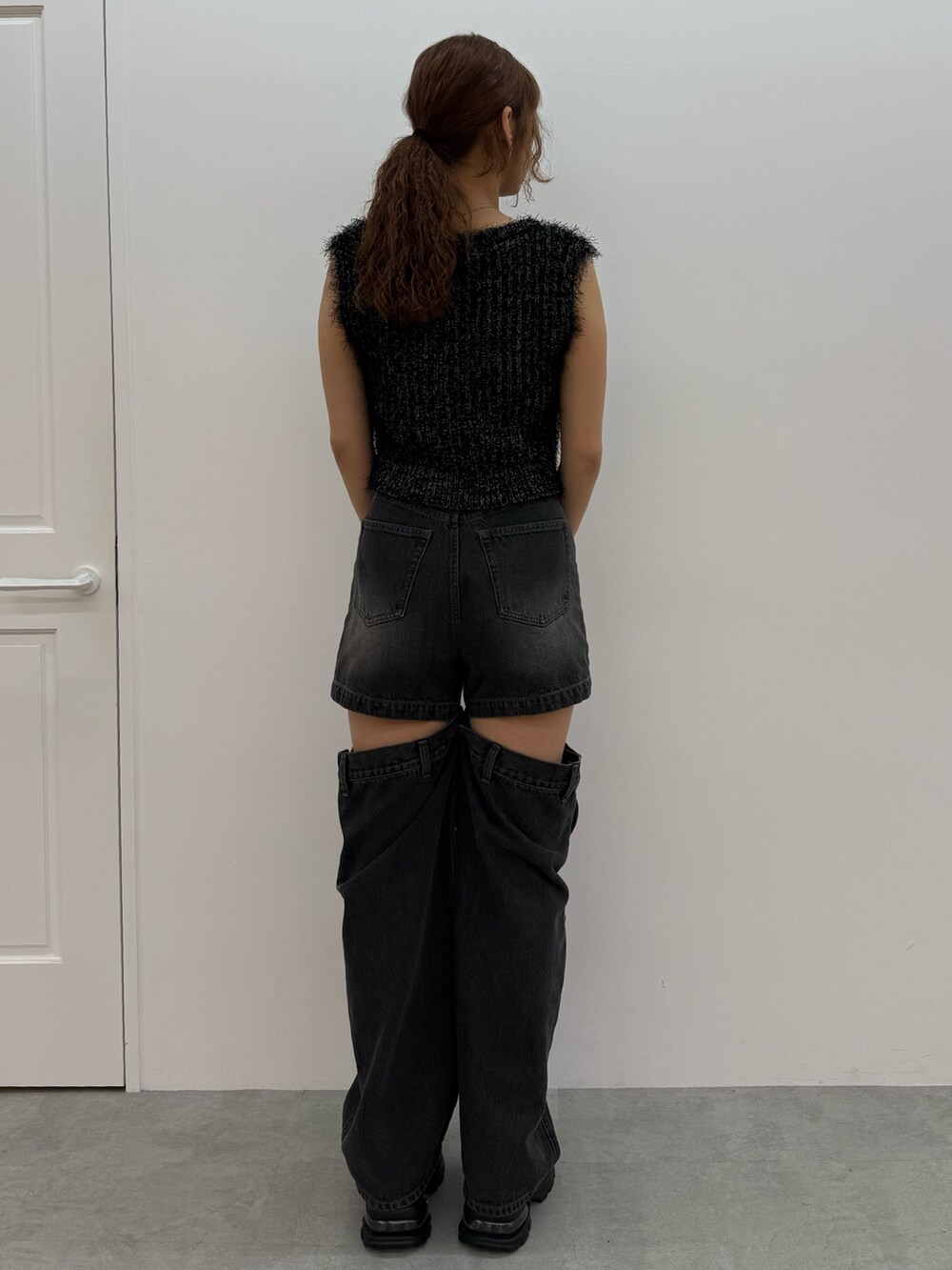 ブラック系のニット/セーター、ブラック系のデニムパンツ、ブラック系のハンドバッグを着用したレディースの夏コーディネートの3枚目の写真