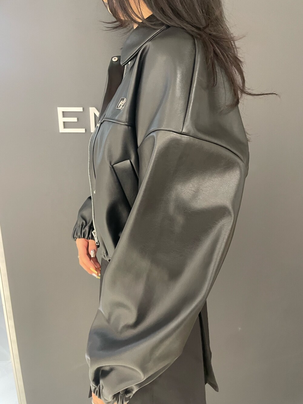 ホワイト系のタンクトップ、ブラック系のブルゾン、ブラック系のスカートを着用したレディースの春コーディネートの5枚目の写真