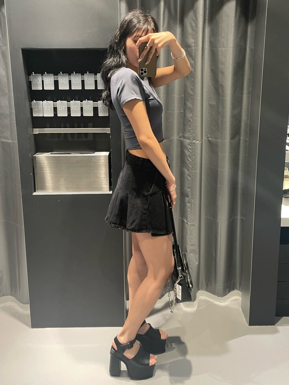 グレー系のTシャツ/カットソー、ブラック系のデニムスカート、ブラック系のショルダーバッグを着用したレディースの春コーディネートの2枚目の写真