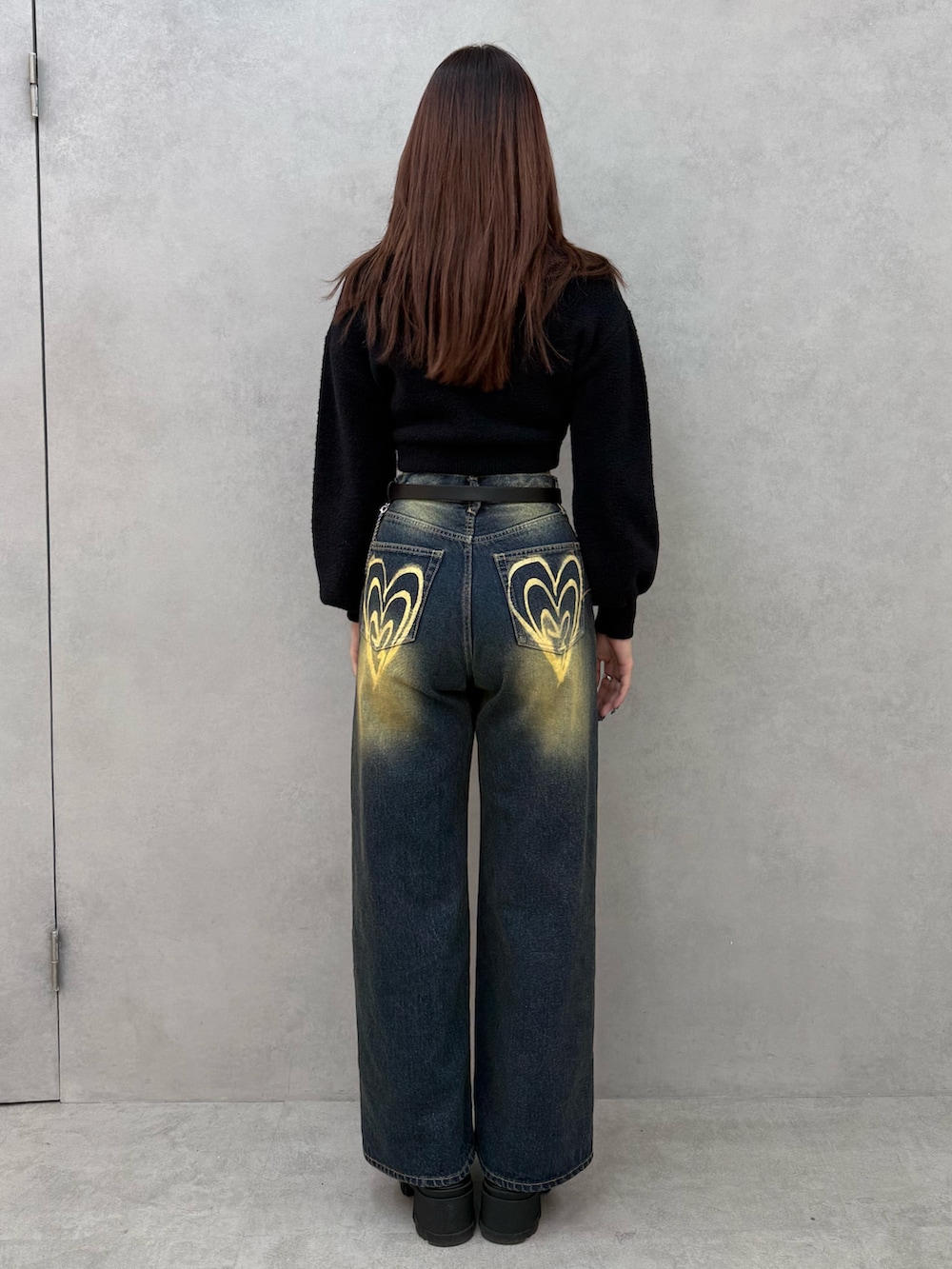 ブラック系のニット/セーター、ブルー系のデニムパンツ、ブラック系のブーツを着用したレディースの冬コーディネートの3枚目の写真