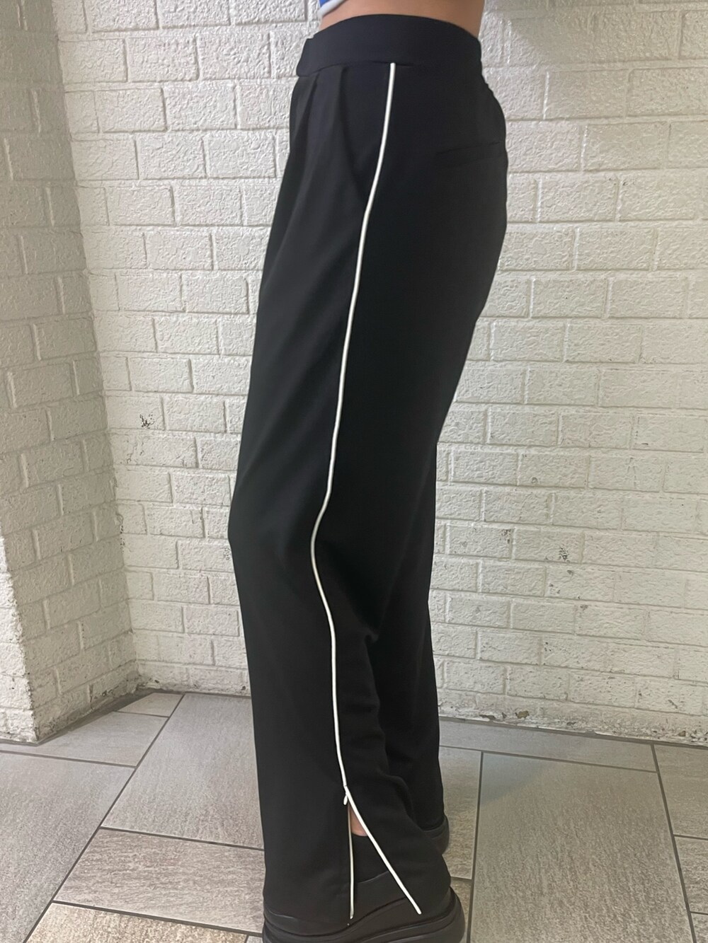 ブラック系のTシャツ/カットソー、ブラック系のスラックス、グレー系のブーツを着用したレディースの冬コーディネートの6枚目の写真