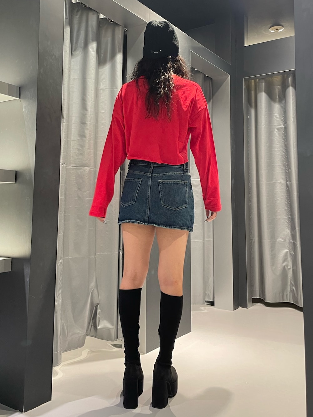 レッド系のTシャツ/カットソー、ブルー系のデニムスカート、その他のブーツを着用したレディースの秋コーディネートの3枚目の写真