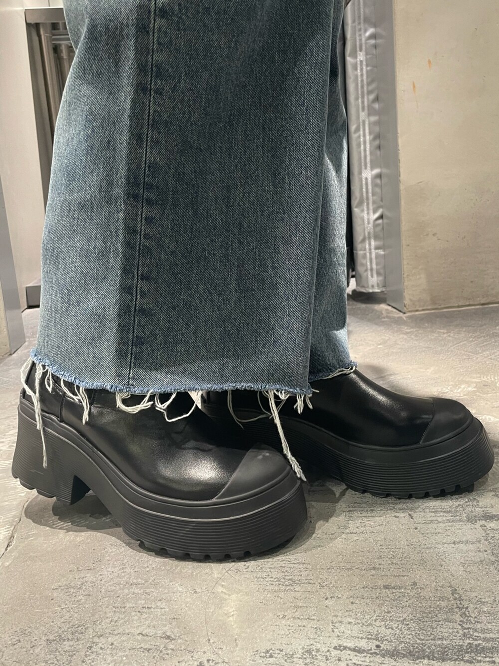 ブルー系のデニムパンツ、ブラック系のブーツ、ブラック系のハンドバッグを着用したレディースの秋コーディネートの7枚目の写真